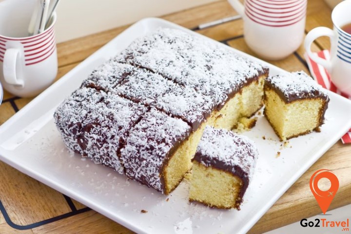 Lamington được làm từ cốt gato rồi phủ lên một lớp socola ấm mịn và được khoác thêm lớp áo dừa trắng tinh, thơm ngọt